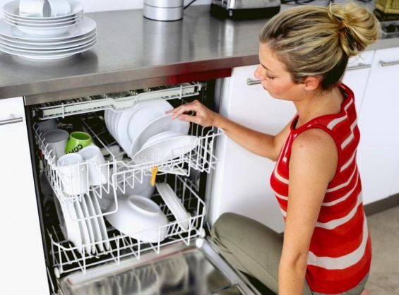 Девушка достает тарелки из посудомоечной машины