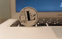 Монетка Litecoin возле ноутбука