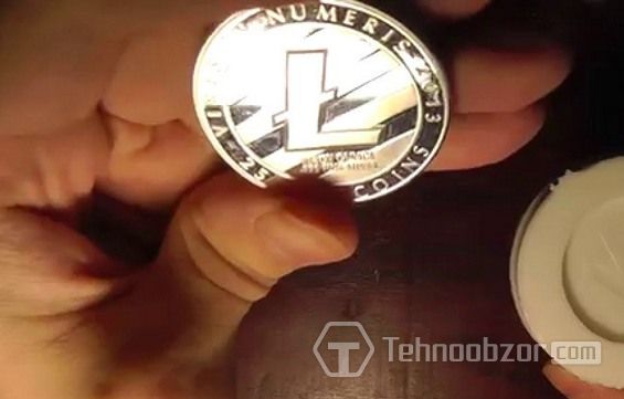 Монета Litecoin зажата между пальцами