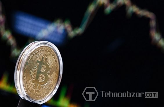 Монета Bitcoin и график, показывающий изменения курса