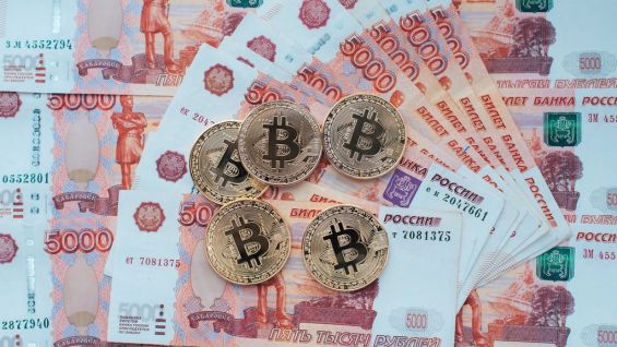 Монеты Bitcoin лежат на рублёвых банкнотах