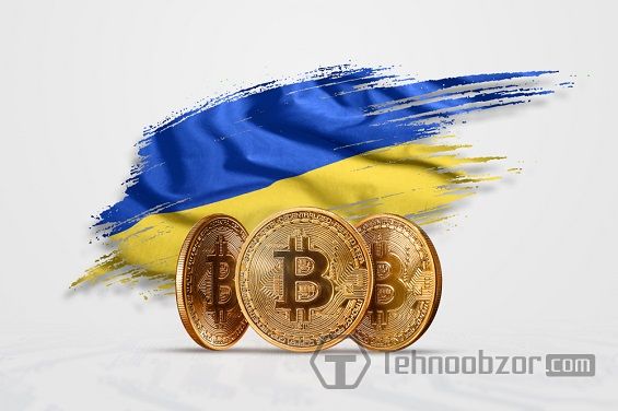 Три монетки Биткоин на фоне украинского флага