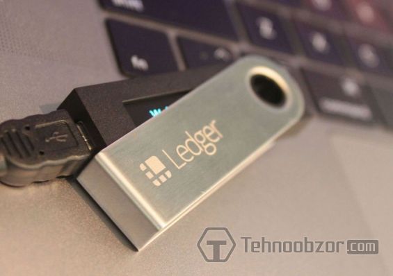 Кошелек Ledger Nano S лежит возле клавиатуры ноутбука