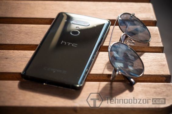 Смартфон HTC U12 Plus лежит возле очков