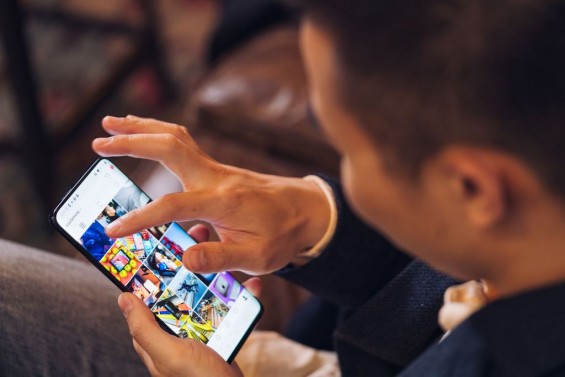 Парень просматривает Instagram на смартфоне OnePlus 7 Pro